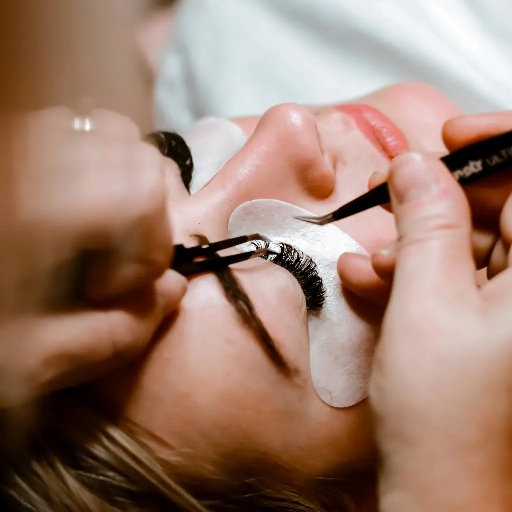 Close up of lash tech applying lash extensions