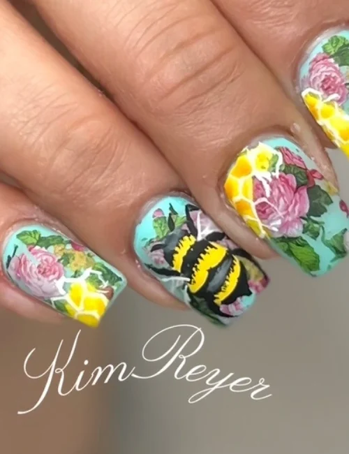Close up of clients nails with flowers, bees and honey combs
