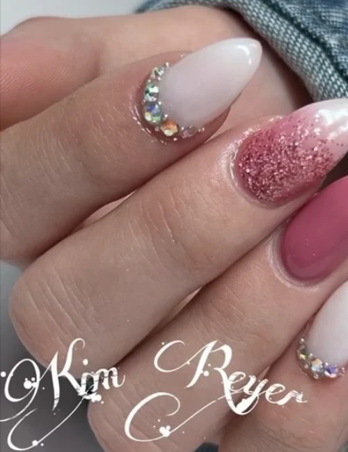 Close up of a hand with a fresh hard gel nail, set painted pink and with with gems.